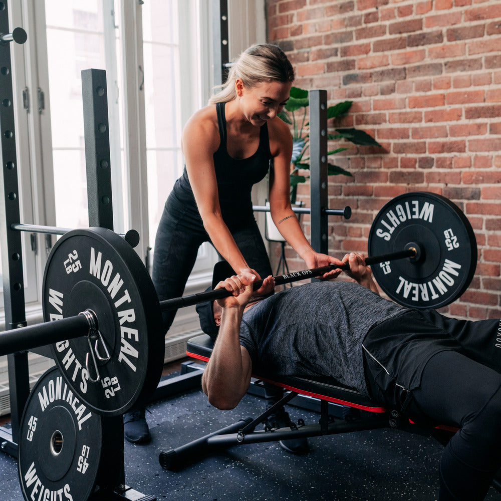 woman spotting man on bench press