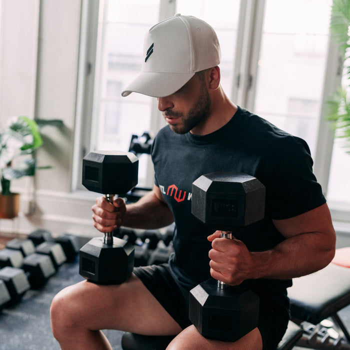 man sitting on bench holding dumbbells